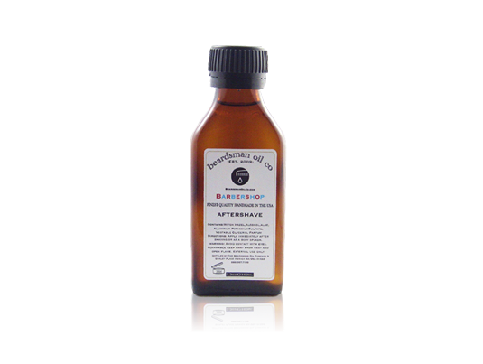 A small amber glass bottle of Beardsman Oil Co. after shave with a black ribbed cap and a white label, centered on a white background with a faint reflection below.